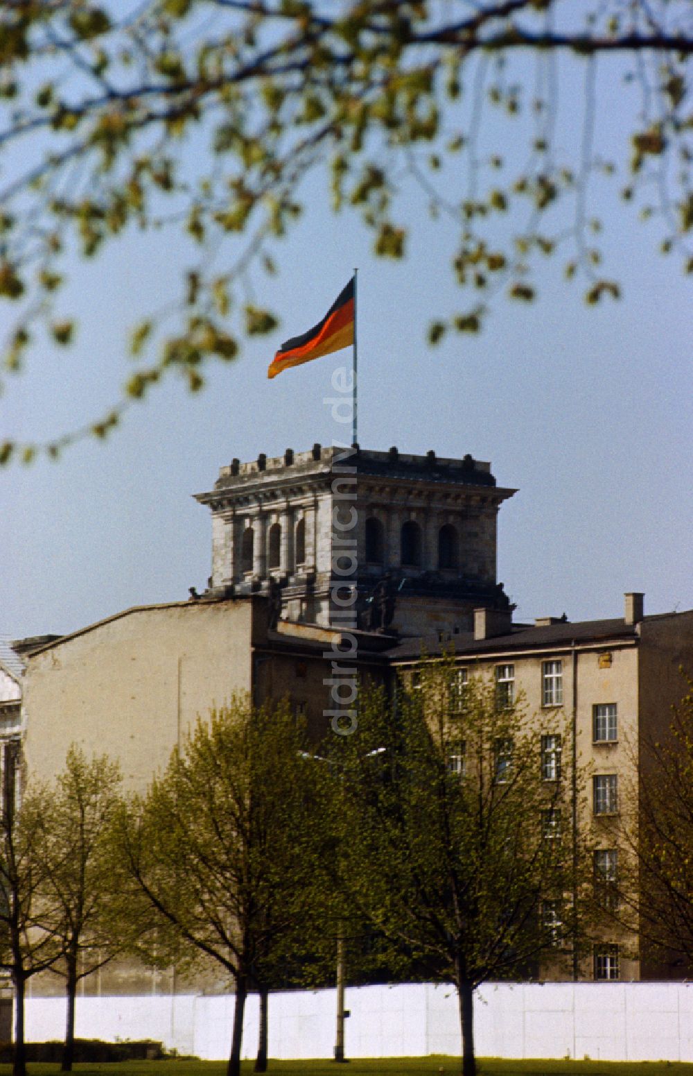DDR-Bildarchiv: Berlin - Blick über die Mauer in Richtung Reichstag mit Turm und Deutschland Flagge in Ostberlin in der DDR