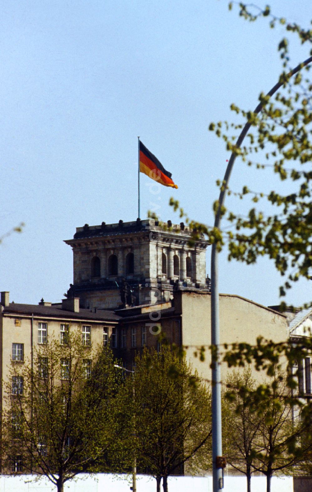 DDR-Fotoarchiv: Berlin - Blick über die Mauer in Richtung Reichstag mit Turm und Deutschland Flagge in Ostberlin in der DDR