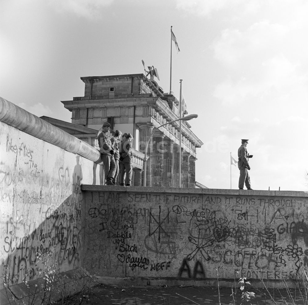 Berlin - Mitte: DDR-Grenzsoldaten auf der Mauer vor dem Brandenburger Tor in Berlin