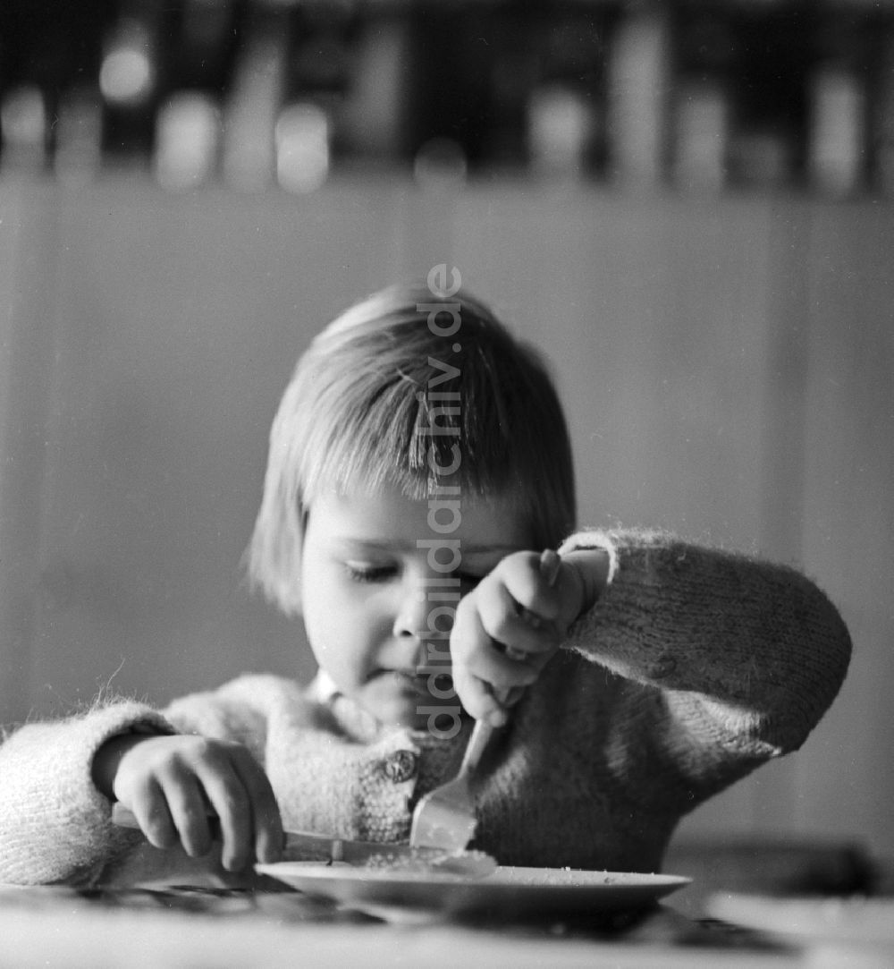 DDR-Fotoarchiv: Berlin - Ein Kind isst mit Messer und Gabel in Berlin, der ehemaligen Hauptstadt der DDR, Deutsche Demokratische Republik