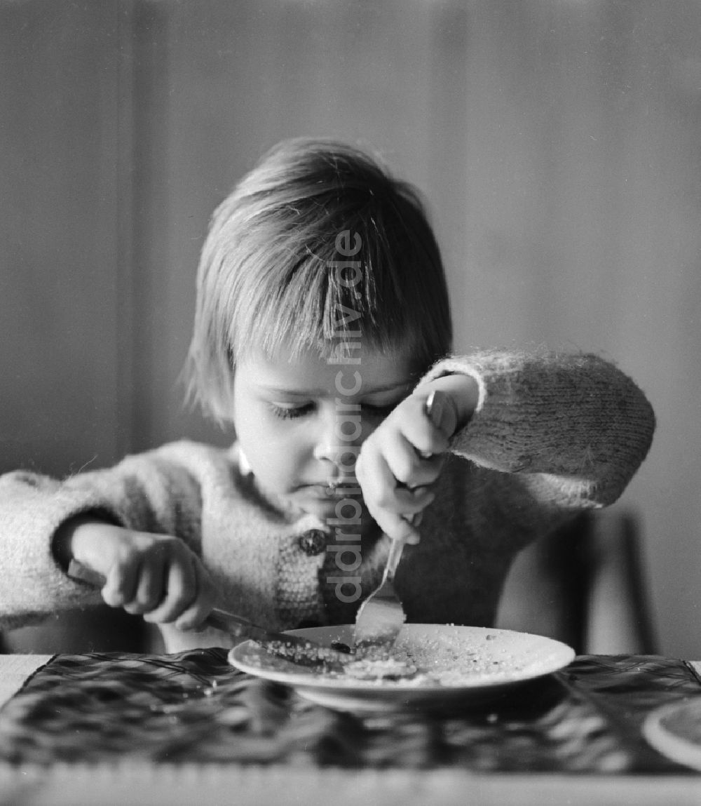 Berlin: Ein Kind isst am Tisch mit Messer und Gabel in Berlin, der ehemaligen Hauptstadt der DDR, Deutsche Demokratische Republik