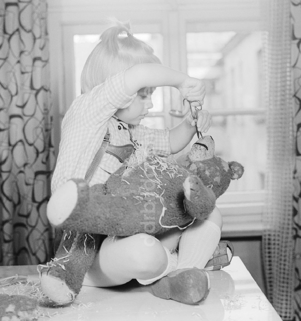DDR-Bildarchiv: Berlin - Ein Kind zerschneidet einen Teddybären in Berlin, der ehemaligen Hauptstadt der DDR, Deutsche Demokratische Republik