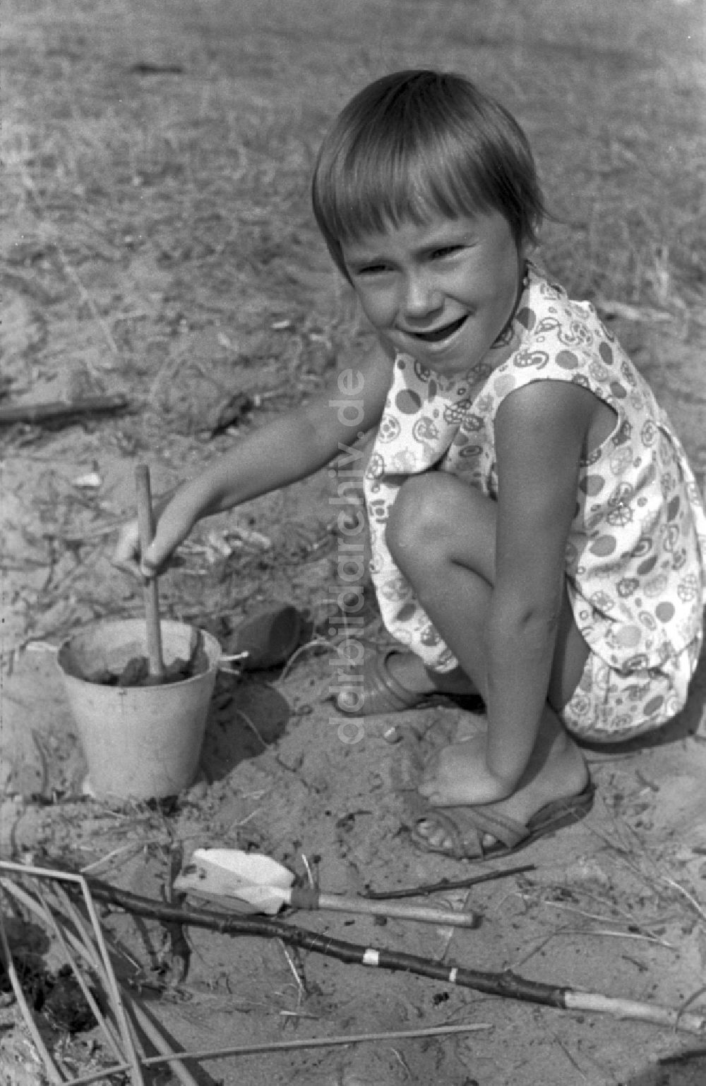 DDR-Fotoarchiv: Neuruppin OT Stendenitz - Ein kleines Kind spielt mit einem Eimer im Sand in Brandenburg