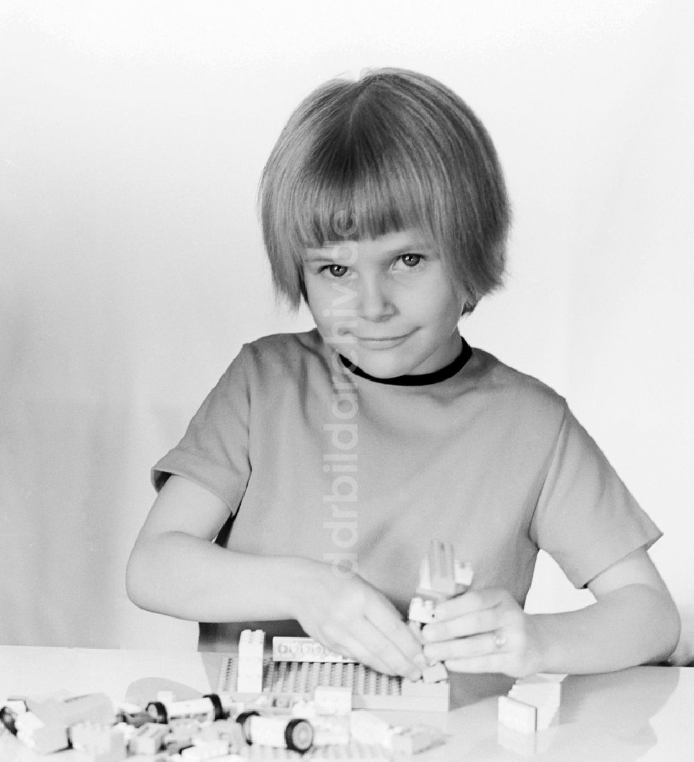 DDR-Fotoarchiv: Berlin - Ein kleines Kind spielt mit Plastik Bausteinen in Berlin, der ehemaligen Hauptstadt der DDR, Deutsche Demokratische Republik