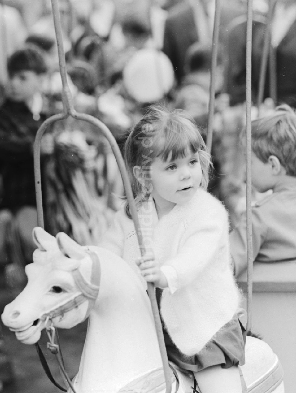Berlin: Ein kleines Mädchen auf einem Karussellpferd in Berlin, der ehemaligen Hauptstadt der DDR, Deutsche Demokratische Republik