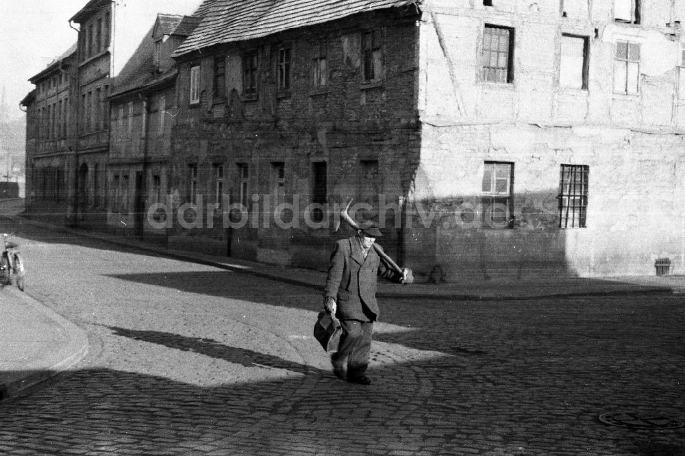 DDR-Bildarchiv: Merseburg - Ein älterer Mann mit Spitzhacke ist auf dem Weg nach Hause in Merseburg in Sachsen-Anhalt in Deutschland