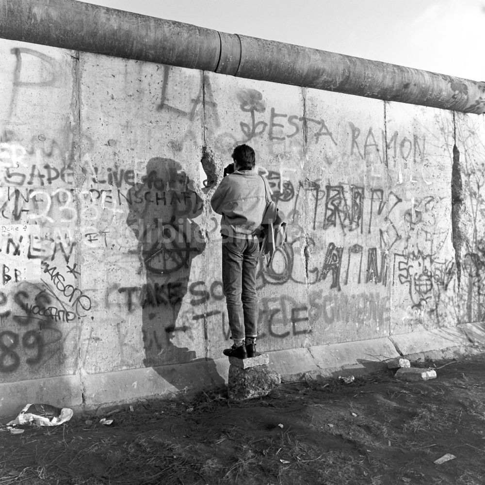 DDR-Bildarchiv: Berlin - Mitte - Ein Mann fotografiert durch einen Spalt in der Berliner Mauer in Berlin