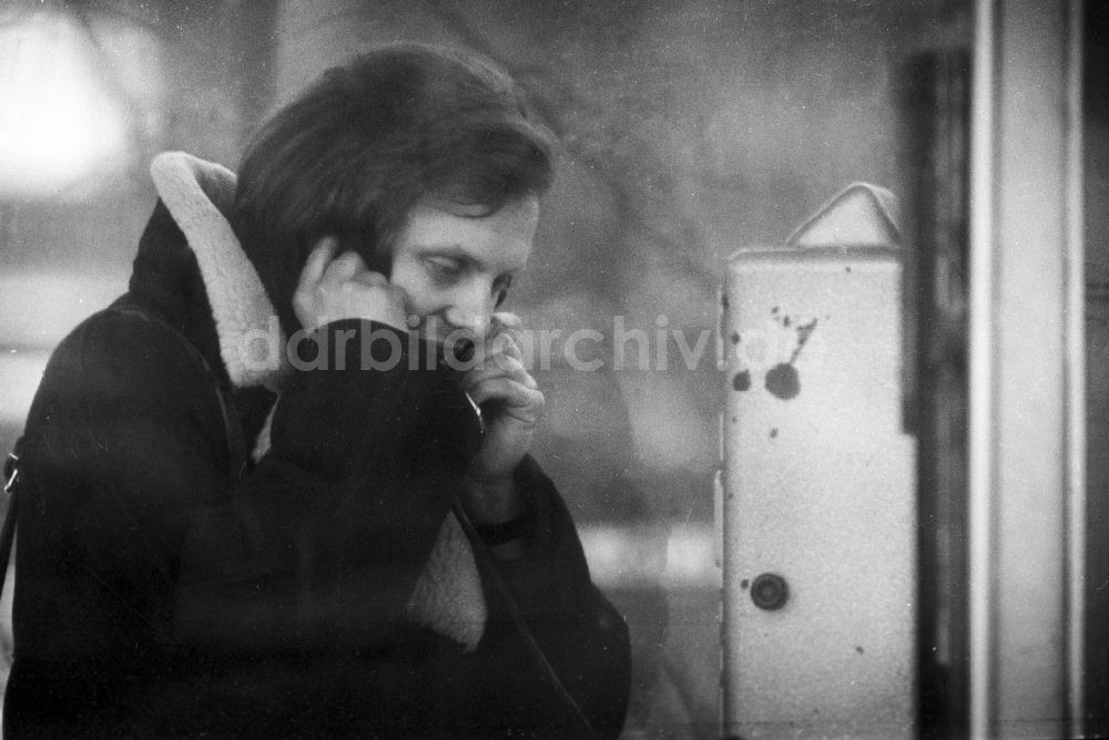 DDR-Fotoarchiv: Berlin - Ein Mann telefoniert mit einem Münzfernsprecher in einer öffentlichen Telefonzelle in Berlin, der ehemaligen Hauptstadt der DDR, Deutsche Demokratische Republik