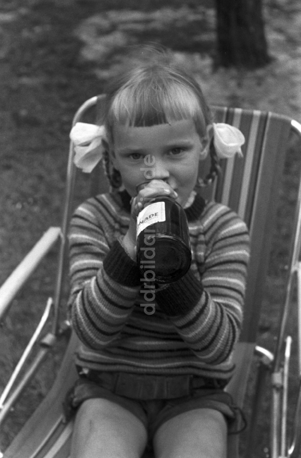 DDR-Fotoarchiv: Malge - Ein Mädchen mit Zöpfen trinkt aus einer Glasflasche Limonade in Malge