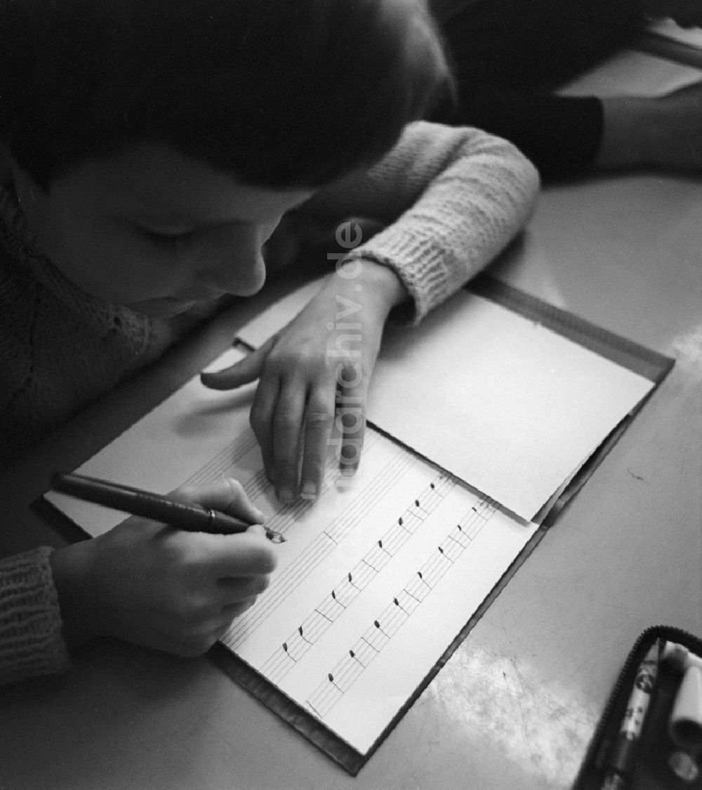 DDR-Fotoarchiv: Berlin - Ein Schüler schreibt mit Füller Noten in sein Notenheft in Berlin