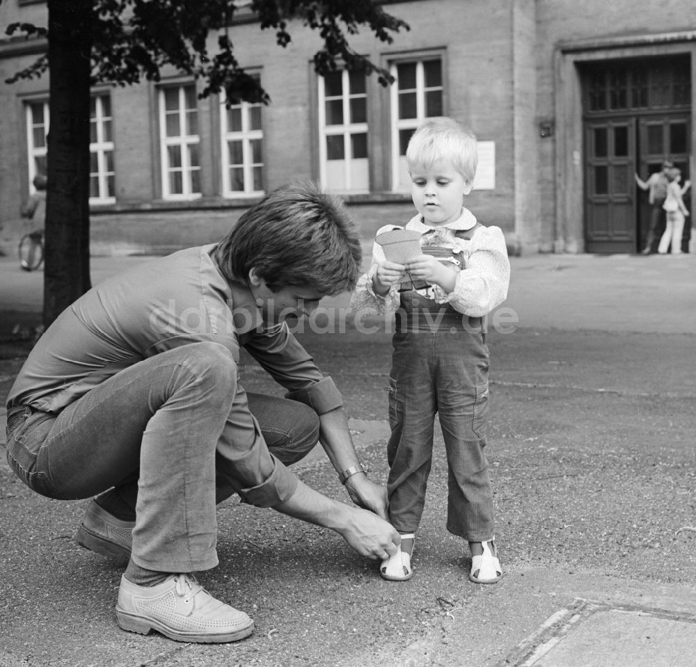 Berlin: Ein Vater bindet seinem Kind die Schuhe zu, in Berlin, der ehemaligen Hauptstadt der DDR, Deutsche Demokratische Republik
