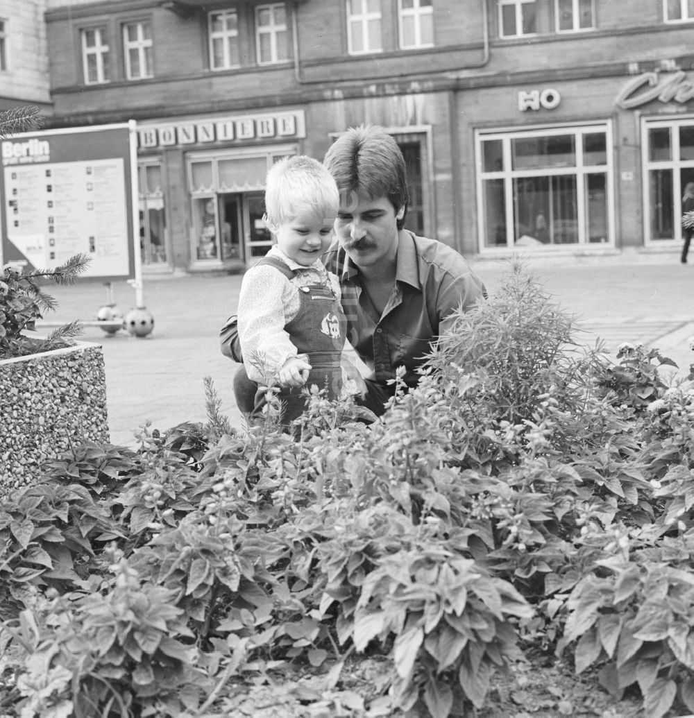 Berlin: Ein Vater steht mit seinem Kind vor einem Blumenbeet in Berlin, der ehemaligen Hauptstadt der DDR, Deutsche Demokratische Republik