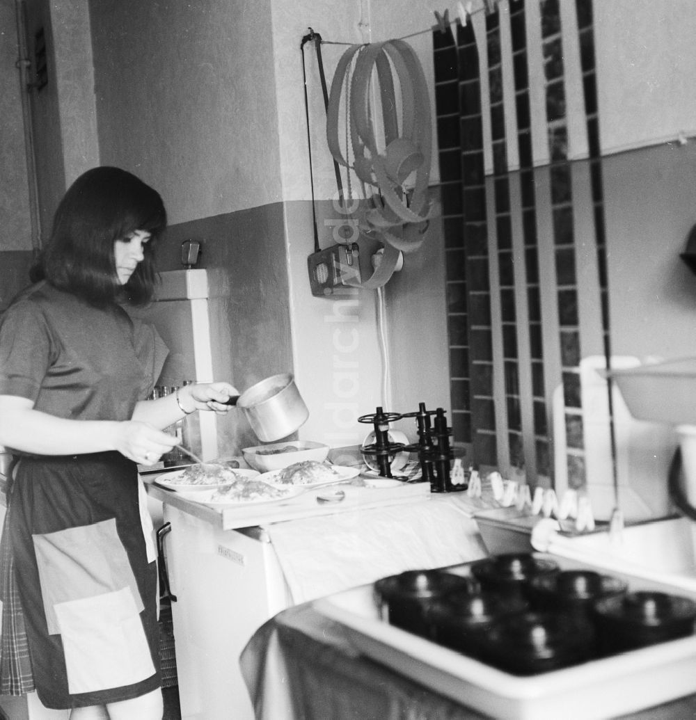 Berlin: Eine Frau bereitet Essen zu, während in der Küche aufgehängte Filme trocknen in Berlin, der ehemaligen Hauptstadt der DDR, Deutsche Demokratische Republik