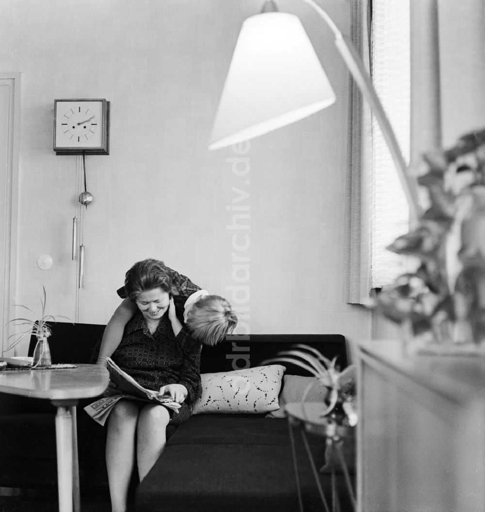 Berlin: Eine Frau sitzt auf dem Sofa und liest eine Zeitung in Berlin, der ehemaligen Hauptstadt der DDR, Deutsche Demokratische Republik