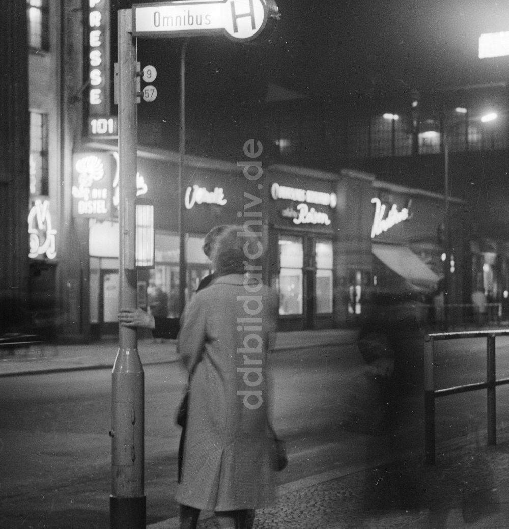 DDR-Fotoarchiv: Berlin - Eine Frau wartet abends an einer Omnibus Haltestelle auf einen Bus an der Friedrichstrasse in Berlin, der ehemaligen Hauptstadt der DDR, Deutsche Demokratische Republik
