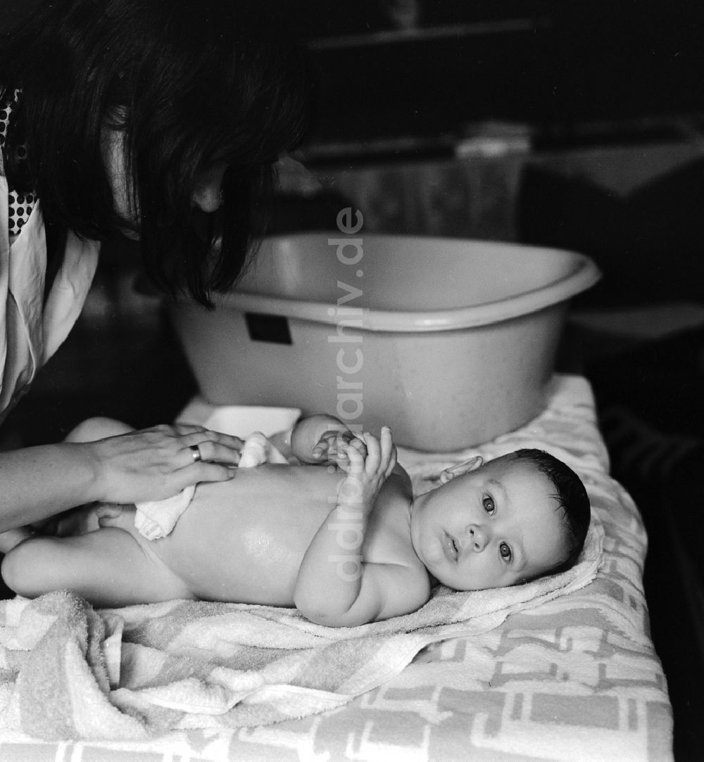 DDR-Fotoarchiv: Berlin - Eine Mutter badet ihr Baby in einer Plastik Badewanne in Berlin, der ehemaligen Hauptstadt der DDR, Deutsche Demokratische Republik