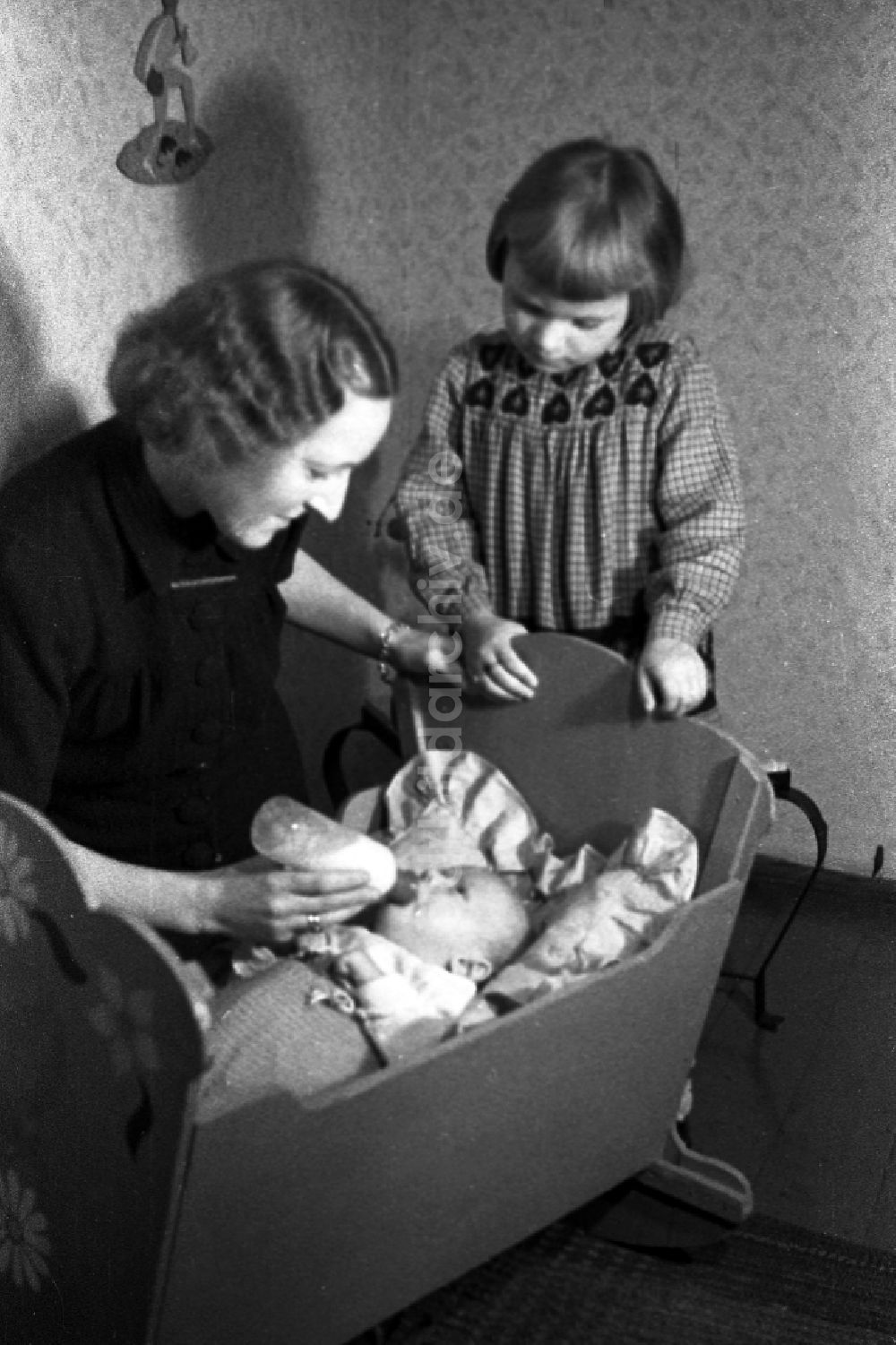DDR-Bildarchiv: Merseburg - Eine Mutter gibt ihrem Baby in der Wiege die Nuckelflasche in Merseburg in Sachsen-Anhalt in der DDR