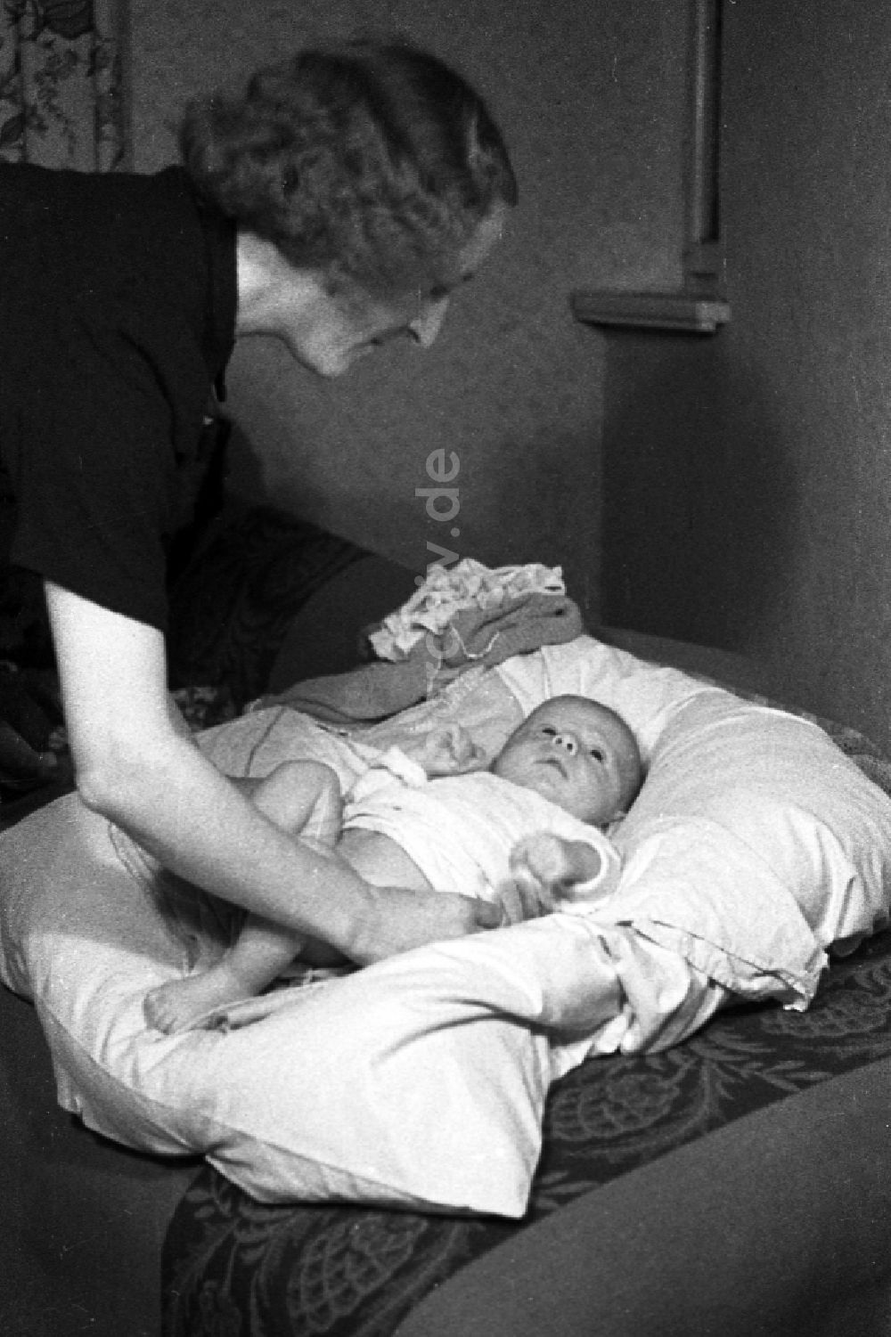 DDR-Fotoarchiv: Merseburg - Eine Mutter wickelt ihr Kind auf einem Kopfkissen in Merseburg in Sachsen-Anhalt in der DDR