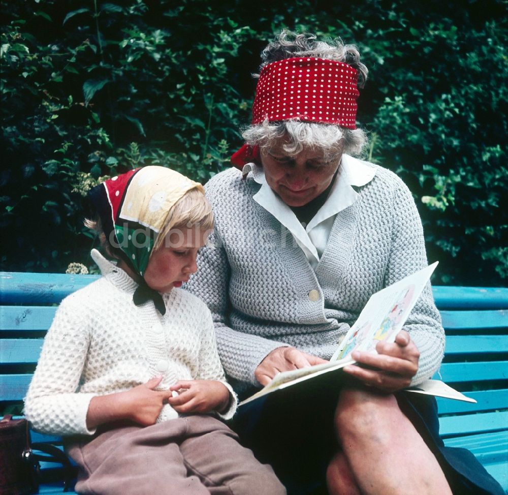 Ahrenshoop: Eine Oma sitzt mit ihrem Enkelkind auf einer Parkbank in Ahrenshoop im Bundesland Mecklenburg-Vorpommern auf dem Gebiet der ehemaligen DDR, Deutsche Demokratische Republik