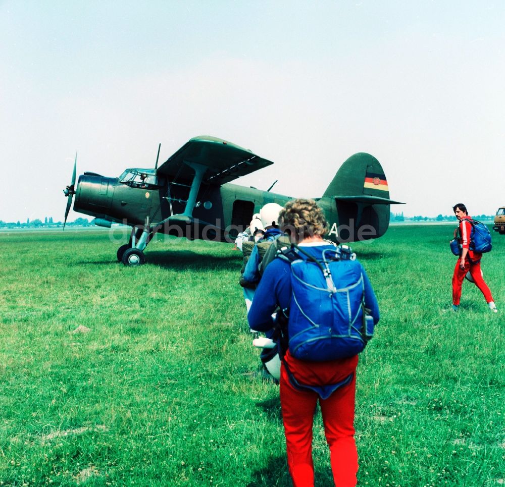 Leipzig: Flugzeug vom Typ Antonow An-2 und Fallschirmspringer auf dem GST Flugplatz in Leipzig-Mockau in Sachsen in der DDR