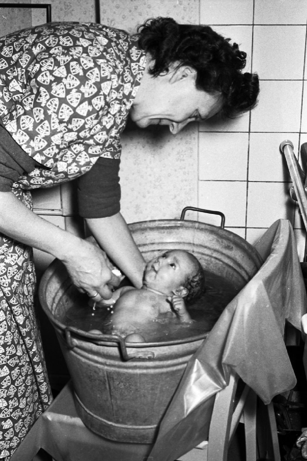 DDR-Bildarchiv: Merseburg - Frau badet ein Baby in einer Zinkwanne in Merseburg in Sachsen-Anhalt in der DDR