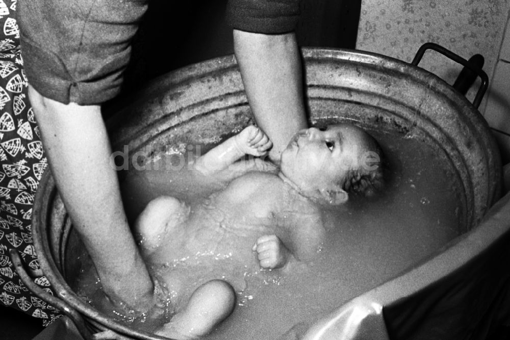 DDR-Fotoarchiv: Merseburg - Frau badet ein Baby in einer Zinkwanne in Merseburg in Sachsen-Anhalt in der DDR