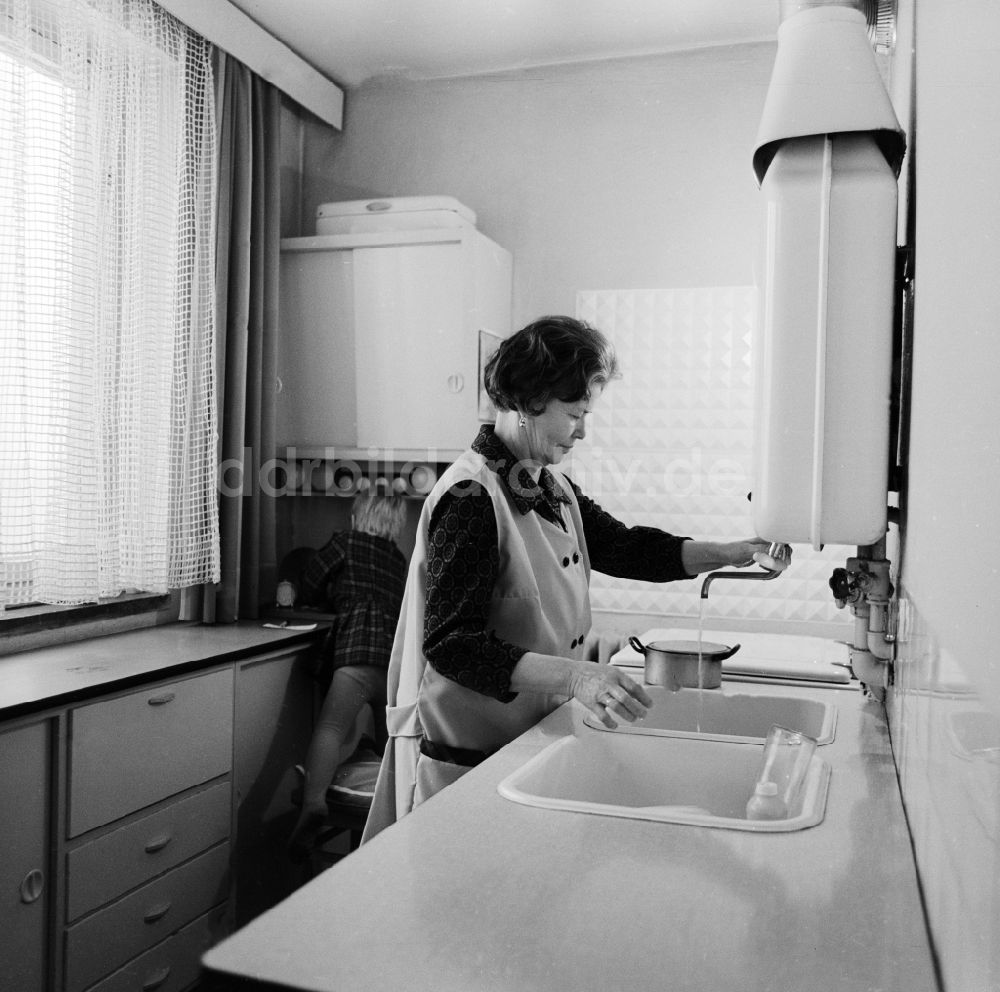 DDR-Fotoarchiv: Berlin - Frau mit Kittelschürze beim abwaschen in der Küche in Berlin, der ehemaligen Hauptstadt der DDR, Deutsche Demokratische Republik