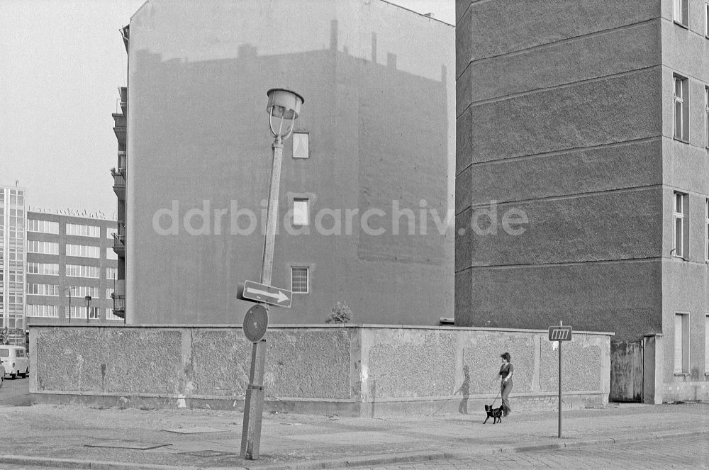 DDR-Fotoarchiv: Berlin - Fußgänger mit Hund an einer schiefen Straßenlaterne im Ortsteil Friedrichshain in Berlin in der DDR