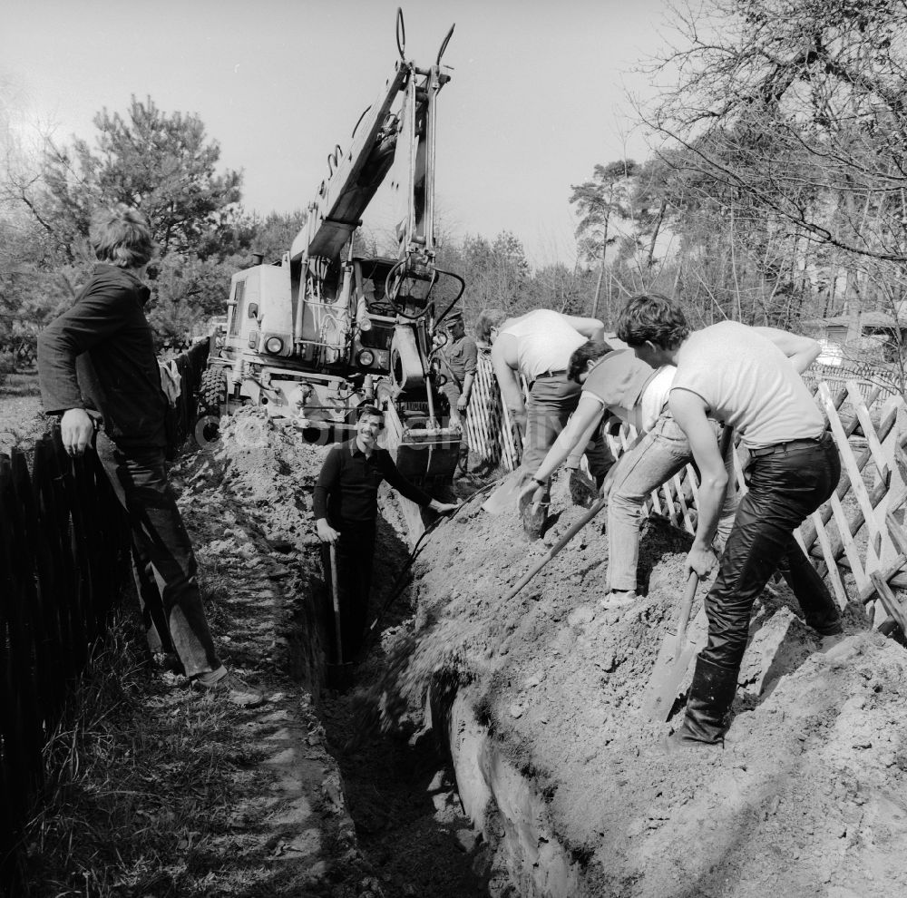 Teupitz: Gartenbesitzer und Anwohner heben gemeinsam einen Kabelgraben aus in Teupitz in Brandenburg in der DDR