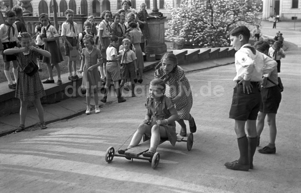 Dresden: Gruppe von Kindern und Jugendlichen mit Pionierkleidung beim Spiel mit selbstgebauten Handwagen vor dem Pionierpalast in Dresden, Deutschland