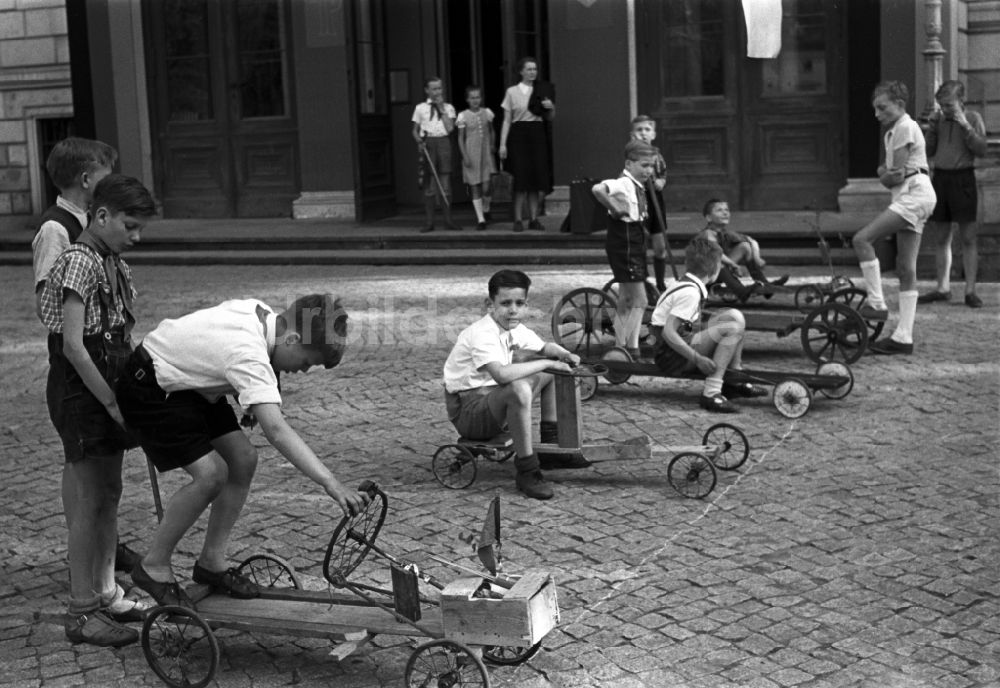 Dresden: Gruppe von Kindern und Jugendlichen mit Pionierkleidung beim Spiel mit selbstgebauten Handwagen vor dem Pionierpalast in Dresden, Deutschland