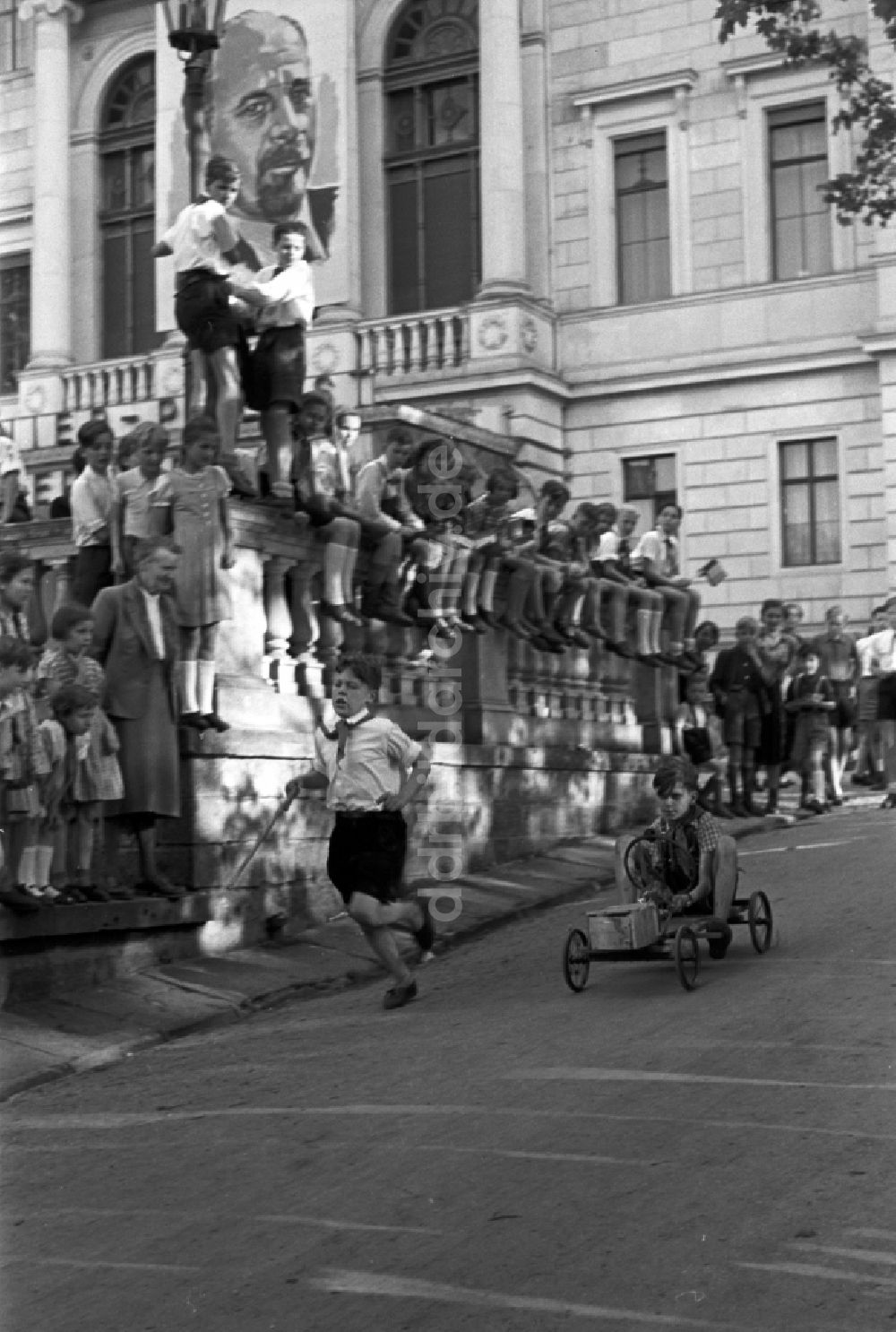 DDR-Fotoarchiv: Dresden - Gruppe von Kindern und Jugendlichen mit Pionierkleidung beim Spiel mit selbstgebauten Handwagen vor dem Pionierpalast in Dresden, Deutschland
