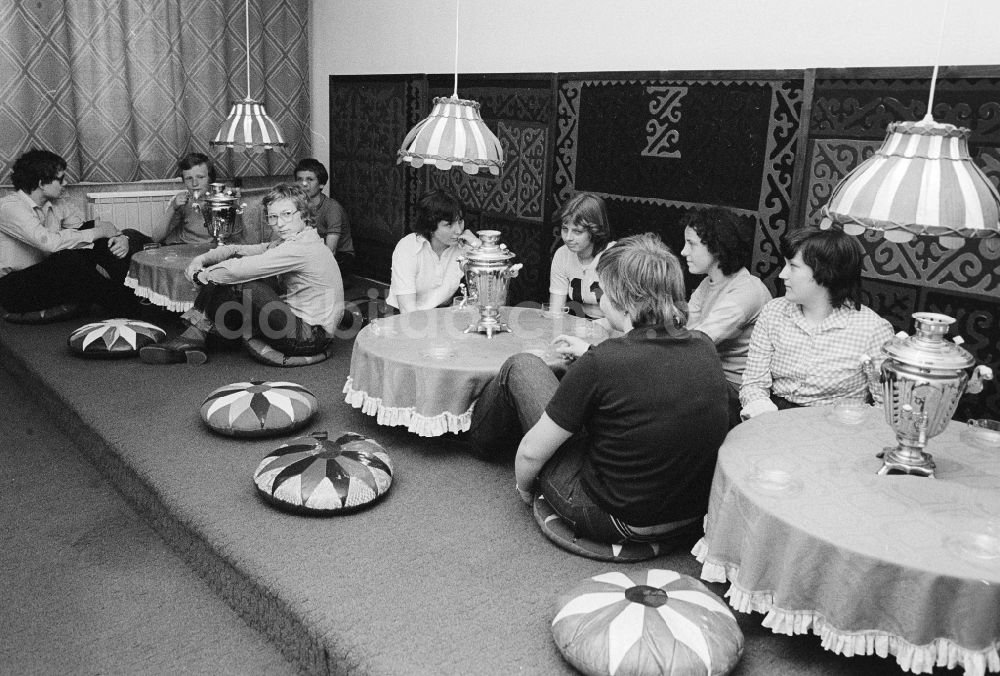 DDR-Fotoarchiv: Berlin - Jugendliche sitzen auf dem Boden in der Teestube im Jugendtouristenhotel Egon Schultz am Tierpark in Berlin, der ehemaligen Hauptstadt der DDR, Deutsche Demokratische Republik
