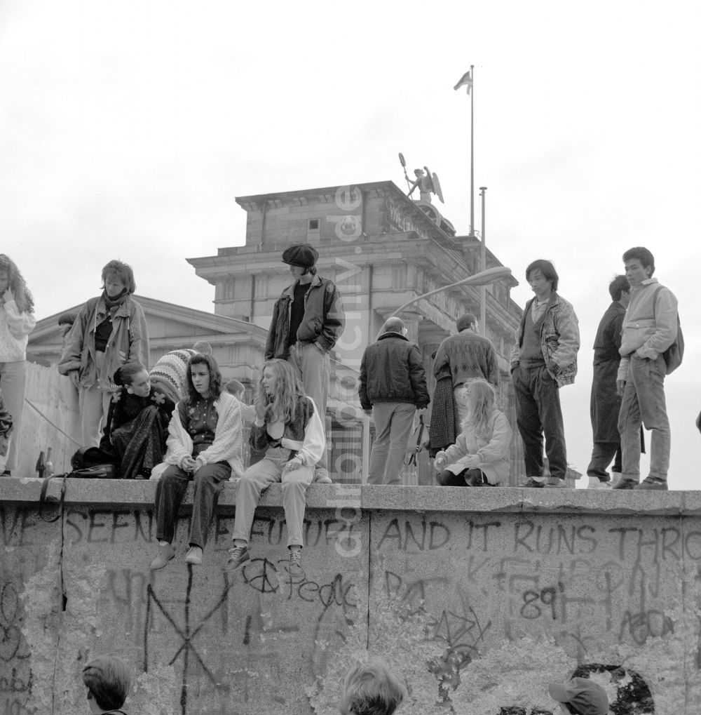 DDR-Fotoarchiv: Berlin - Jugendliche und Touristen sitzen auf der Berliner Mauer am Brandenburger Tor in Berlin