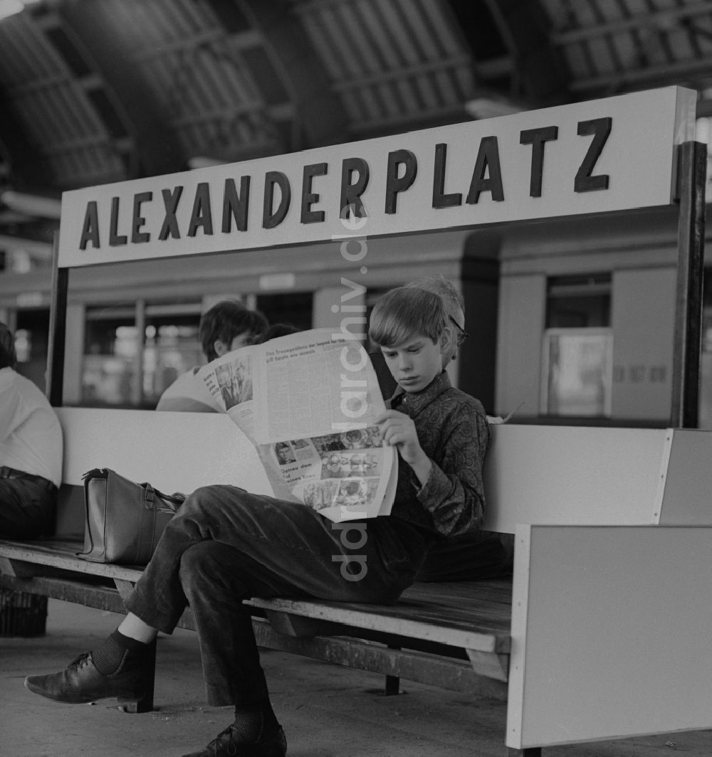 DDR-Fotoarchiv: Berlin - Mitte - Junge liest Zeitung auf einer Bank im Bahnhof Alexanderplatz in Berlin - Mitte
