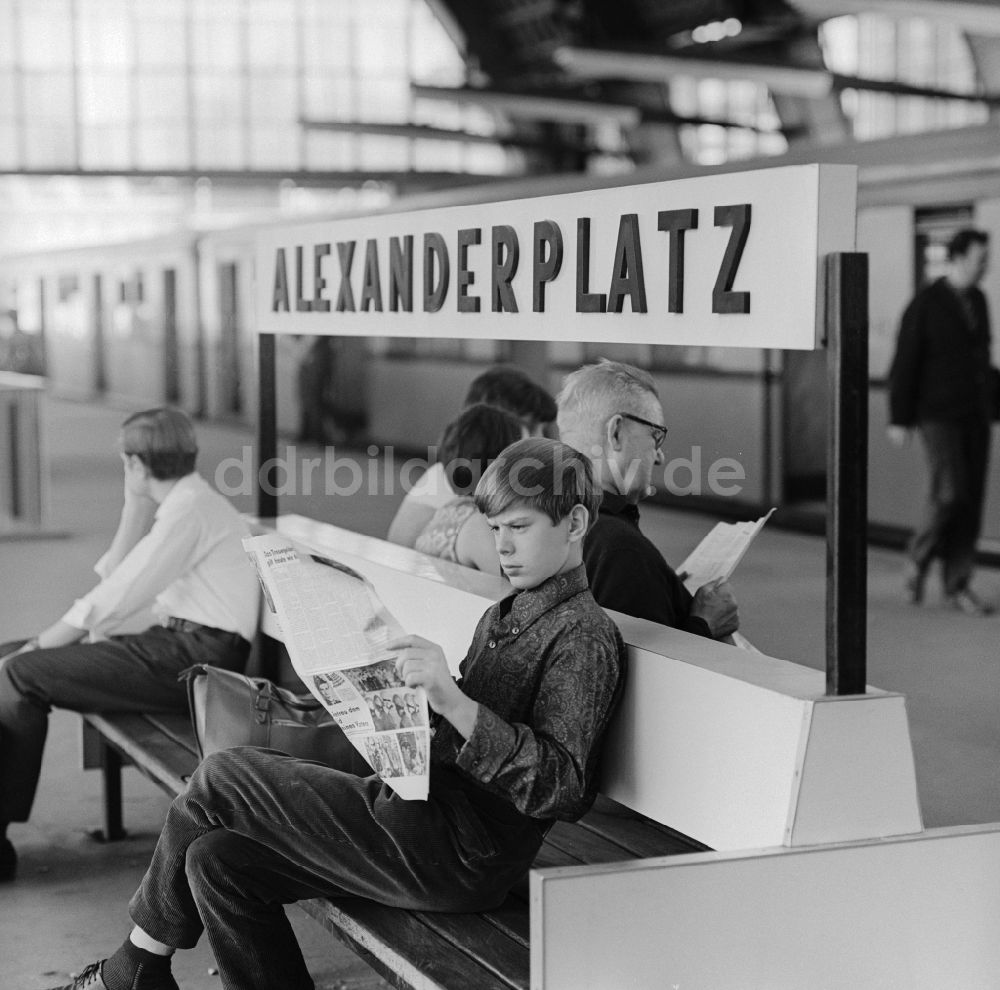 Berlin - Mitte: Junge liest Zeitung auf einer Bank im Bahnhof Alexanderplatz in Berlin - Mitte