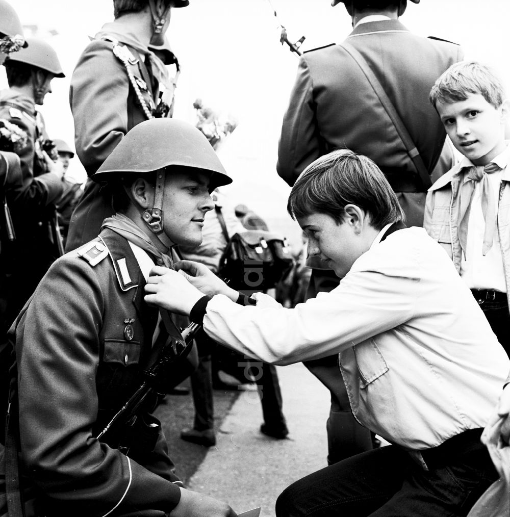 Berlin: Junge Pioniere überreichen Soldaten der NVA Blumen und Halstücher in Berlin, der ehemaligen Hauptstadt der DDR, Deutsche Demokratische Republik