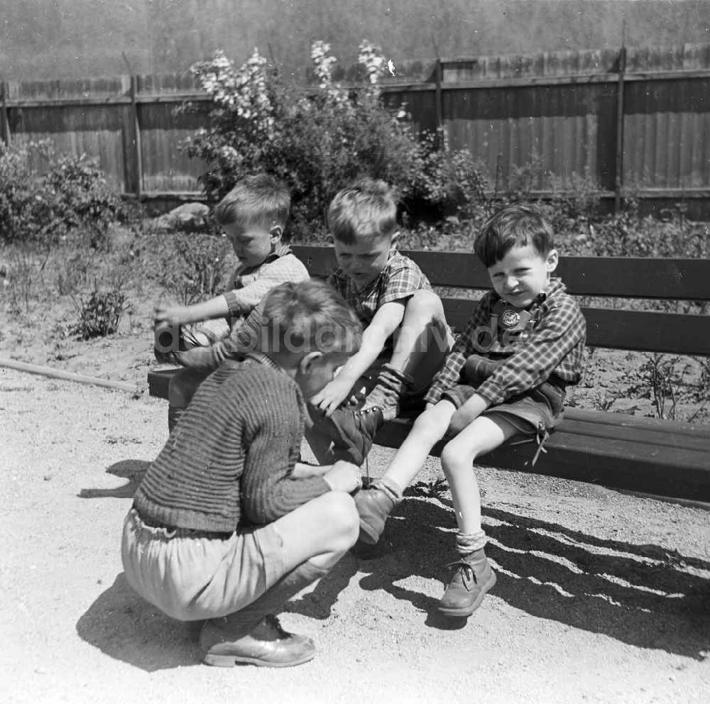Arnstadt: Jungen in kurzen Lederhosen sitzen auf einer Gartenbank in Arnstadt in Thüringen in der DDR