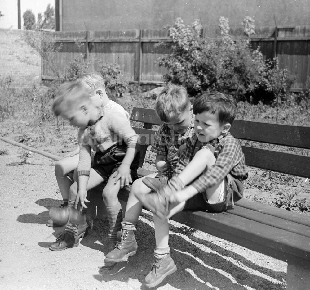 DDR-Bildarchiv: Arnstadt - Jungen in kurzen Lederhosen sitzen auf einer Gartenbank in Arnstadt in Thüringen in der DDR