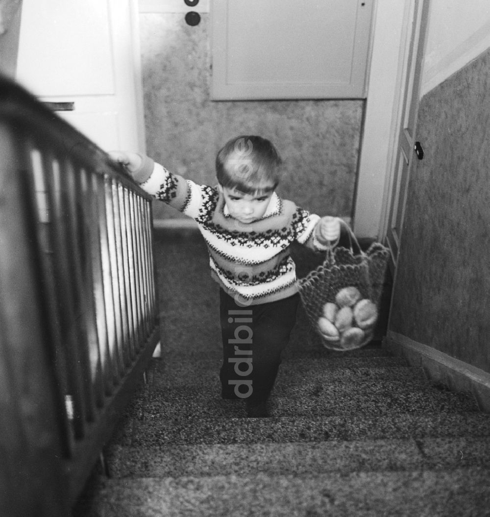 DDR-Bildarchiv: Berlin - Kind trägt ein Einkaufsnetz mit Brötchen in einem Treppenhaus in Berlin, der ehemaligen Hauptstadt der DDR, Deutsche Demokratische Republik