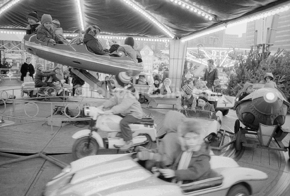 DDR-Fotoarchiv: Berlin - Kinder in einem Kinderkarussell auf dem Berliner Weihnachtsmarkt in Berlin, der ehemaligen Hauptstadt der DDR, Deutsche Demokratische Republik