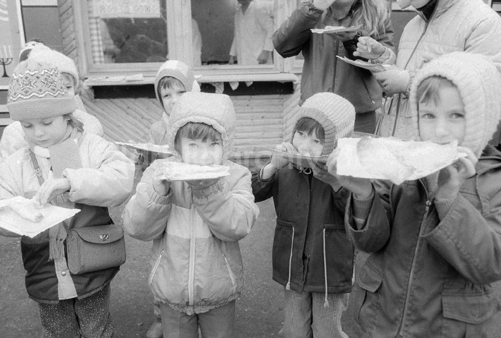 Berlin: Kinder essen gefüllte Eierkuchen auf dem Weihnachtsmarkt in Berlin, der ehemaligen Hauptstadt der DDR, Deutsche Demokratische Republik