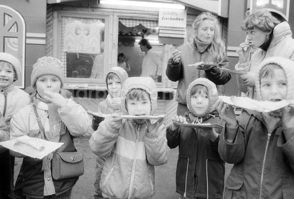 DDR-Bildarchiv: Berlin - Kinder essen gefüllte Eierkuchen auf dem Weihnachtsmarkt in Berlin, der ehemaligen Hauptstadt der DDR, Deutsche Demokratische Republik