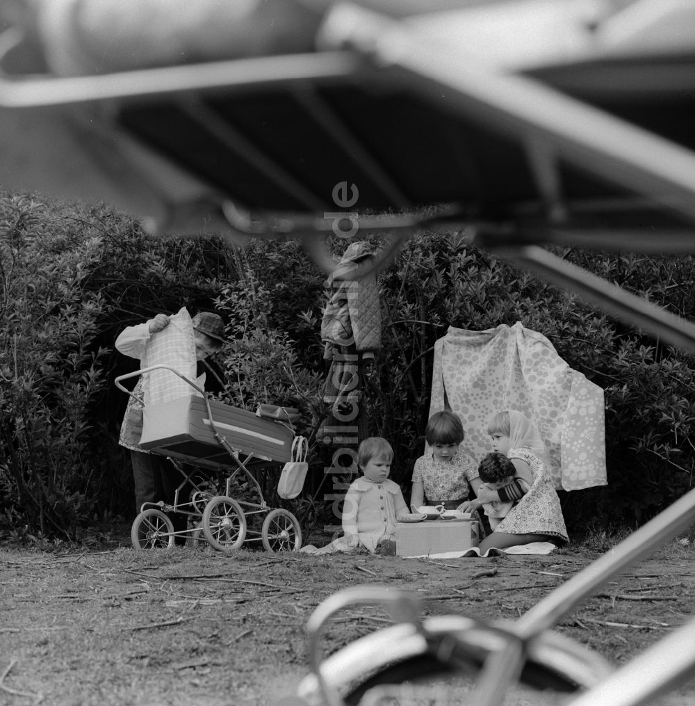 DDR-Fotoarchiv: Berlin - Kinder spielen Mutter Vater Kind in einem Garten in Berlin, der ehemaligen Hauptstadt der DDR, Deutsche Demokratische Republik