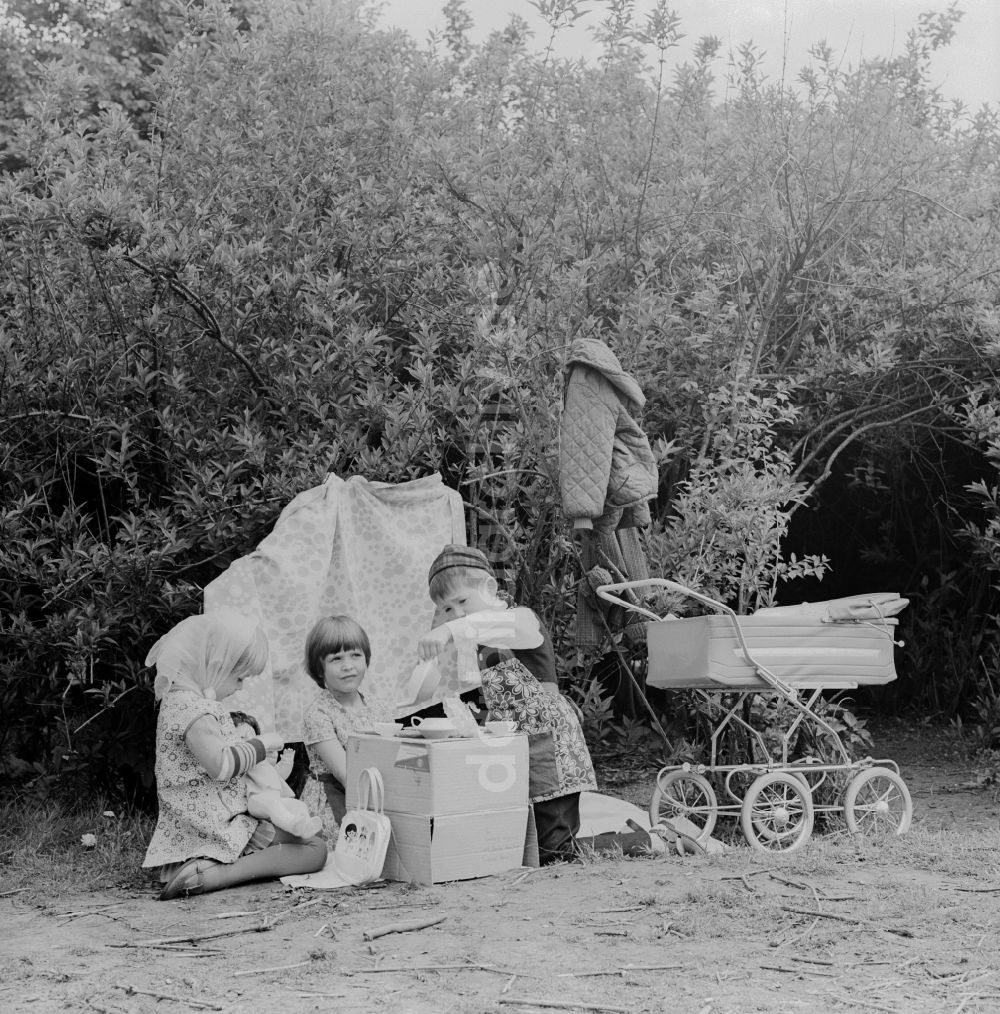 DDR-Fotoarchiv: Berlin - Kinder spielen Mutter Vater Kind in einem Garten in Berlin, der ehemaligen Hauptstadt der DDR, Deutsche Demokratische Republik
