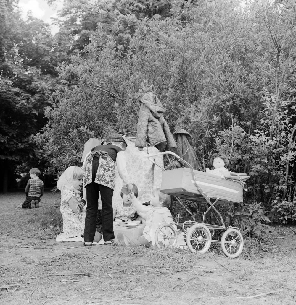 DDR-Bildarchiv: Berlin - Kinder spielen Mutter Vater Kind in einem Garten in Berlin, der ehemaligen Hauptstadt der DDR, Deutsche Demokratische Republik