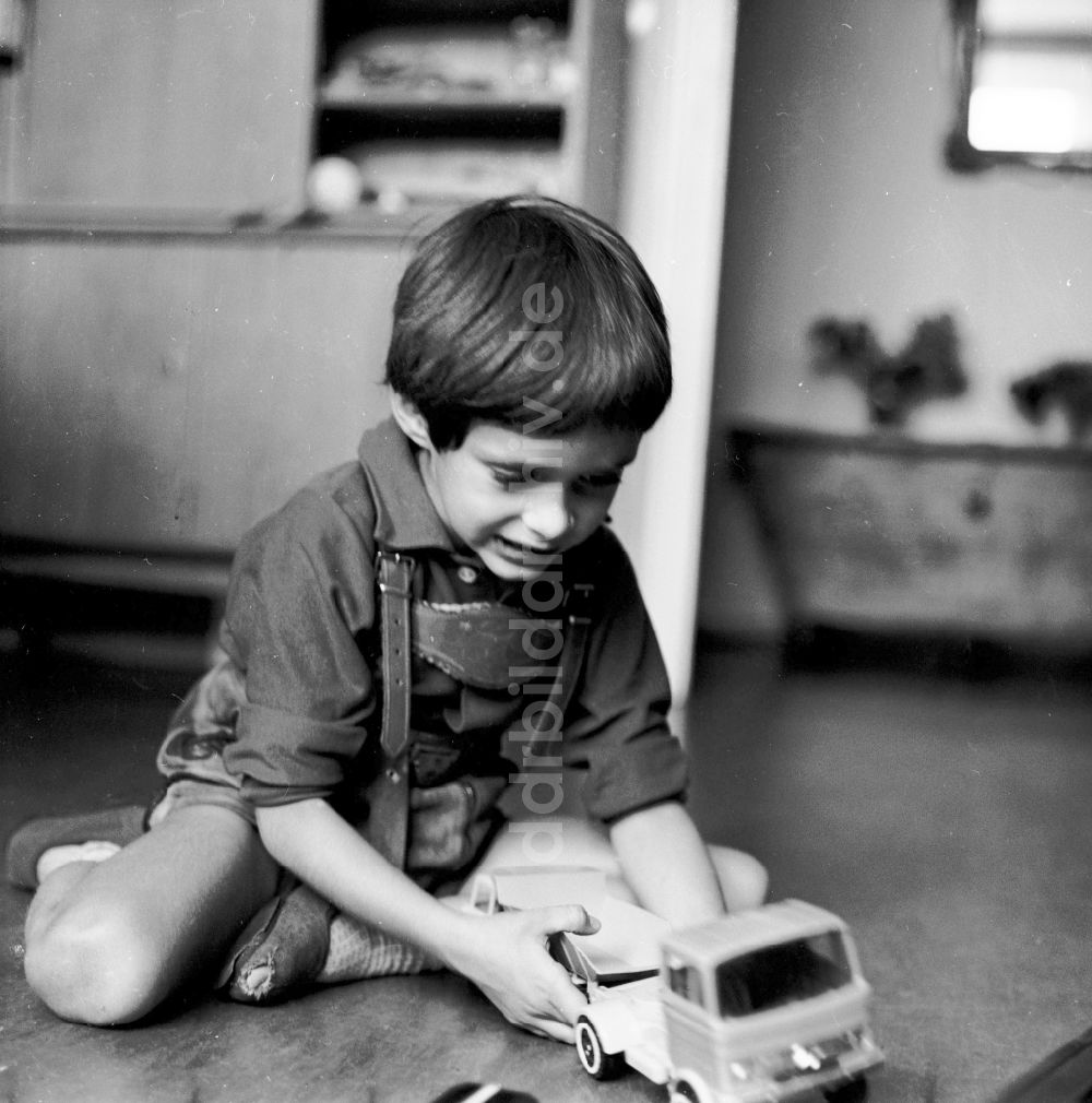 DDR-Fotoarchiv: Berlin - Kleiner Junge spielt mit seinem Spielzeugautos in Berlin, der ehemaligen Hauptstadt der DDR, Deutsche Demokratische Republik
