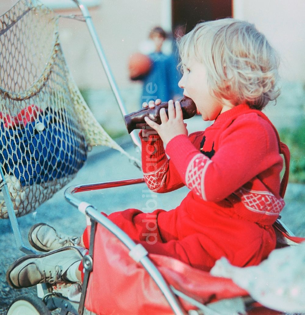 DDR-Fotoarchiv: Schlettau - Kleines Kind beißt herzhaft in einen Schokoladen Hohlkörper in Schlettau im Bundesland Sachsen auf dem Gebiet der ehemaligen DDR, Deutsche Demokratische Republik