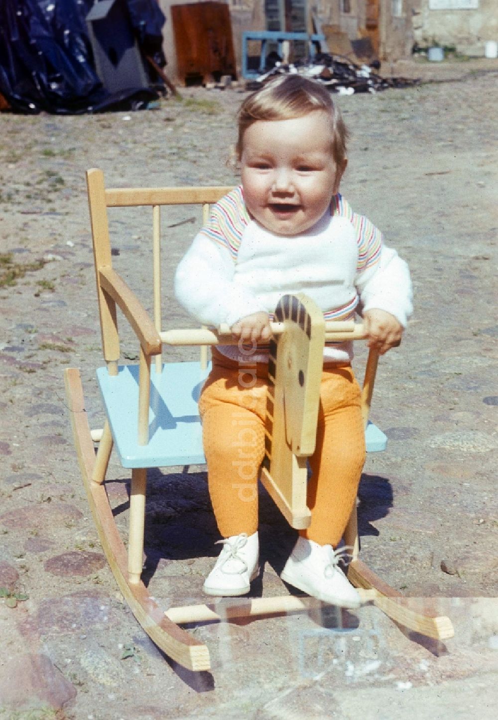 DDR-Fotoarchiv: Neustrelitz - Kleines Kind in einem Holz Schaukelpferd in Neustrelitz in Mecklenburg-Vorpommern in der DDR