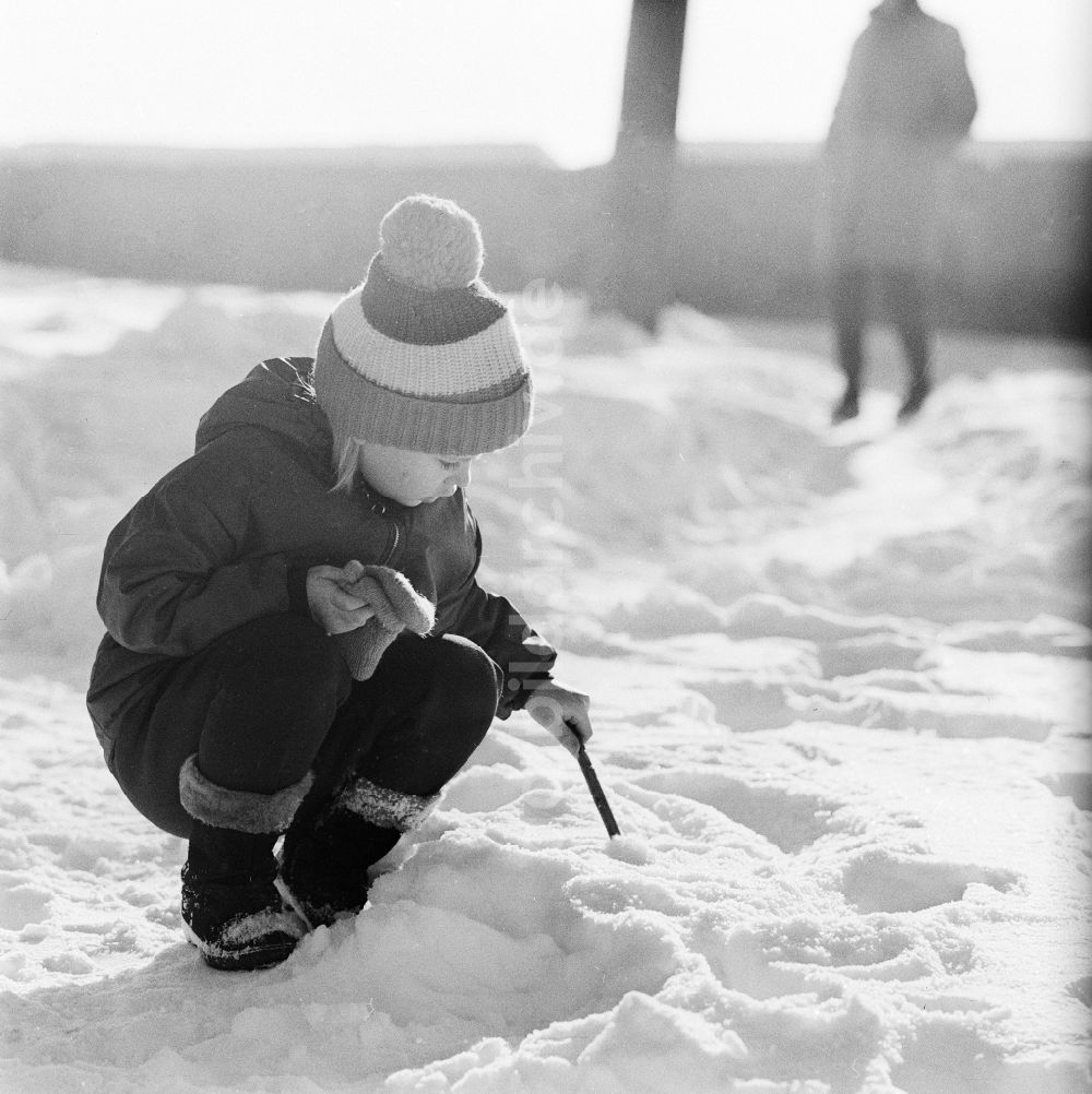 DDR-Bildarchiv: Jena - Kleines Kind mit Pudelmütze spielt im Schnee in Jena in Thüringen in der DDR